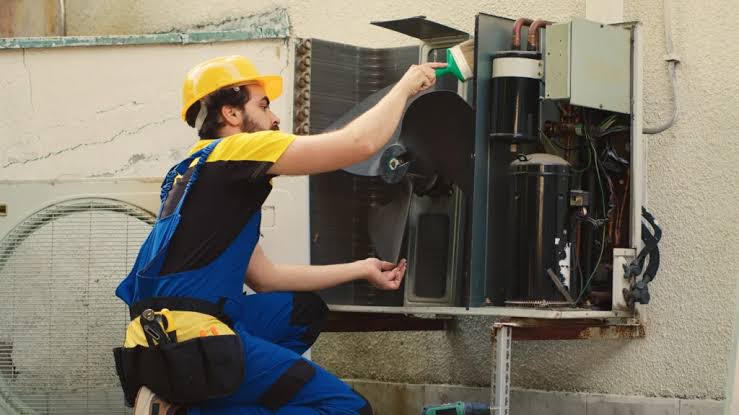 HVAC technician inspecting internal components of an outdoor system