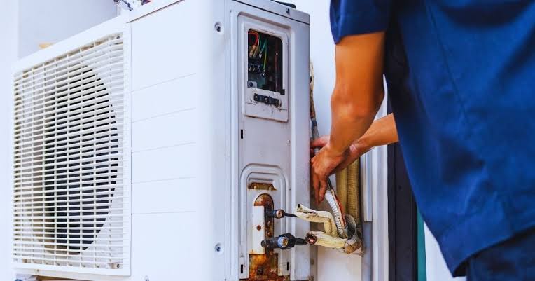 Technician connecting service equipment to an outdoor HVAC system